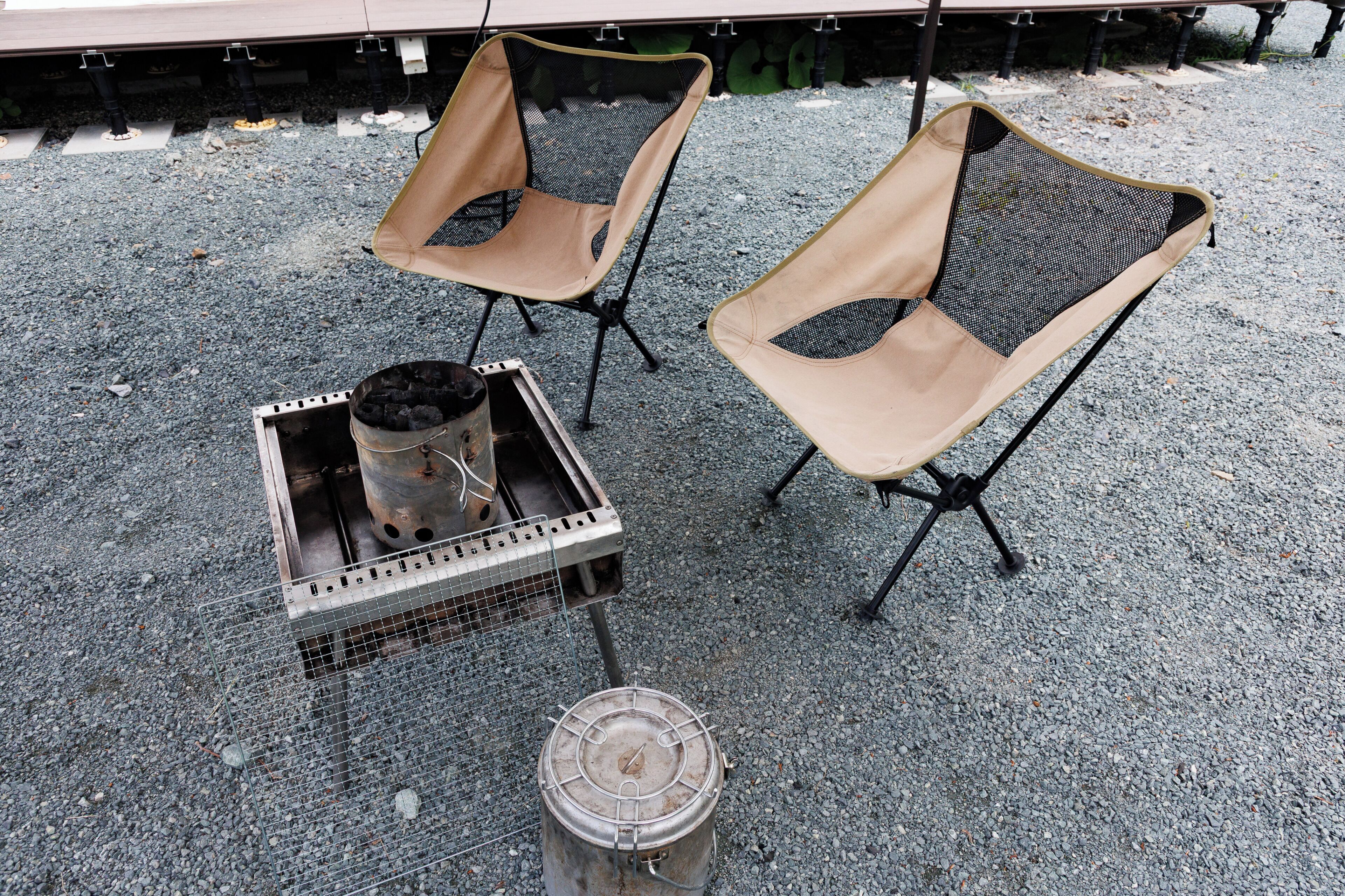 Two outdoor seating areas with metal tables and chairs, a grill, and a metal container.