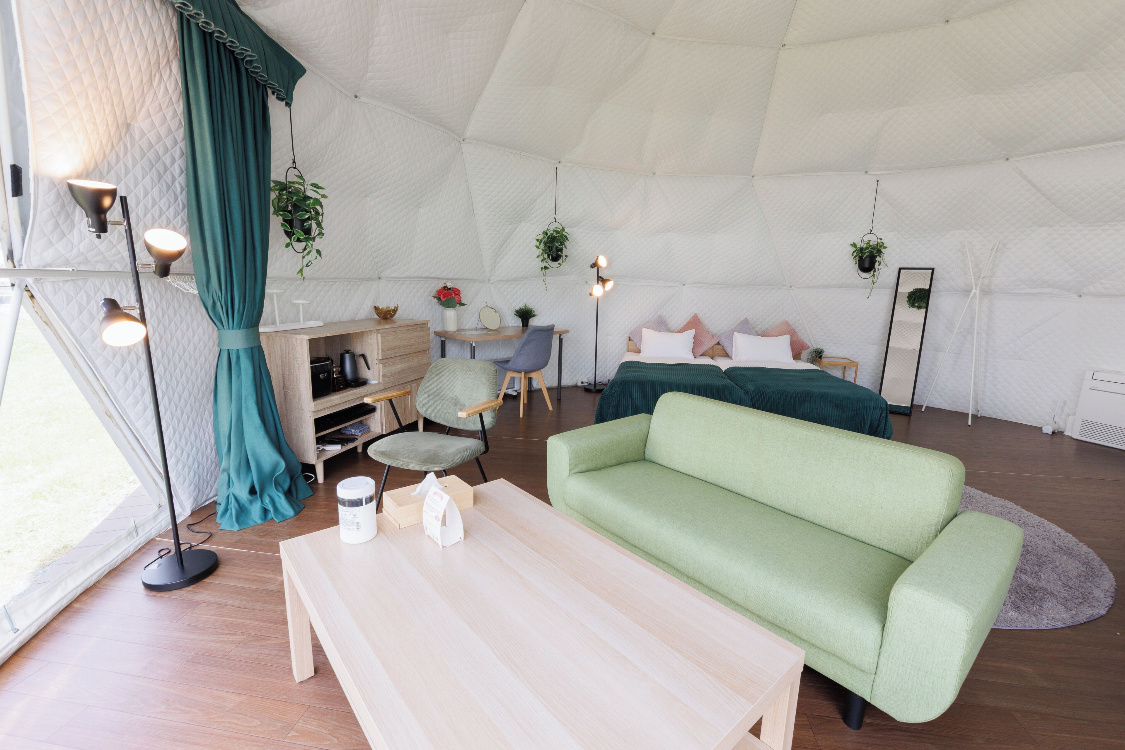 A tented accommodation with a sofa, a coffee table, a desk, and a chair.
