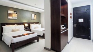 Habitación de hotel con dos camas, un armario de madera oscura, un escritorio con silla y una puerta con cerradura.