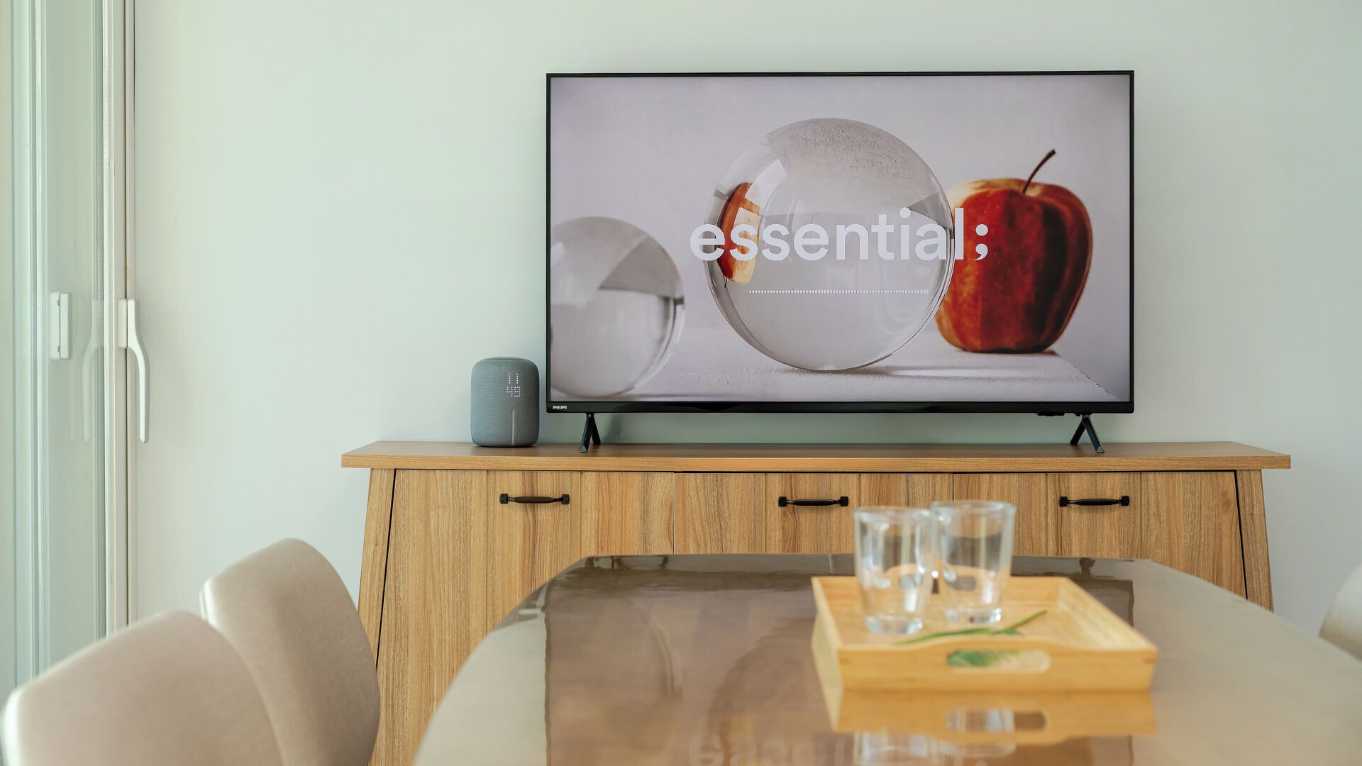 A television on a wooden cabinet with a glass tray on a table in front.