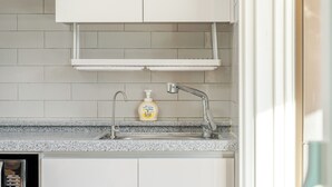 Una cocina con encimera de granito, pileta de acero inoxidable, grifo y dispensador de jabón.