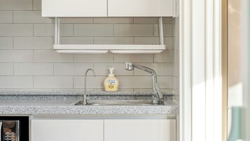 Una cocina con encimera de granito, pileta de acero inoxidable, grifo y dispensador de jabón.