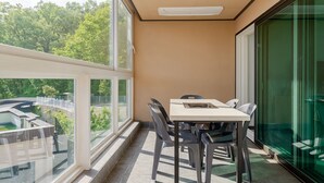 A balcony with a table and chairs, large windows, and a view of greenery. - Migasil Family & Private Pension (Gapyeong)