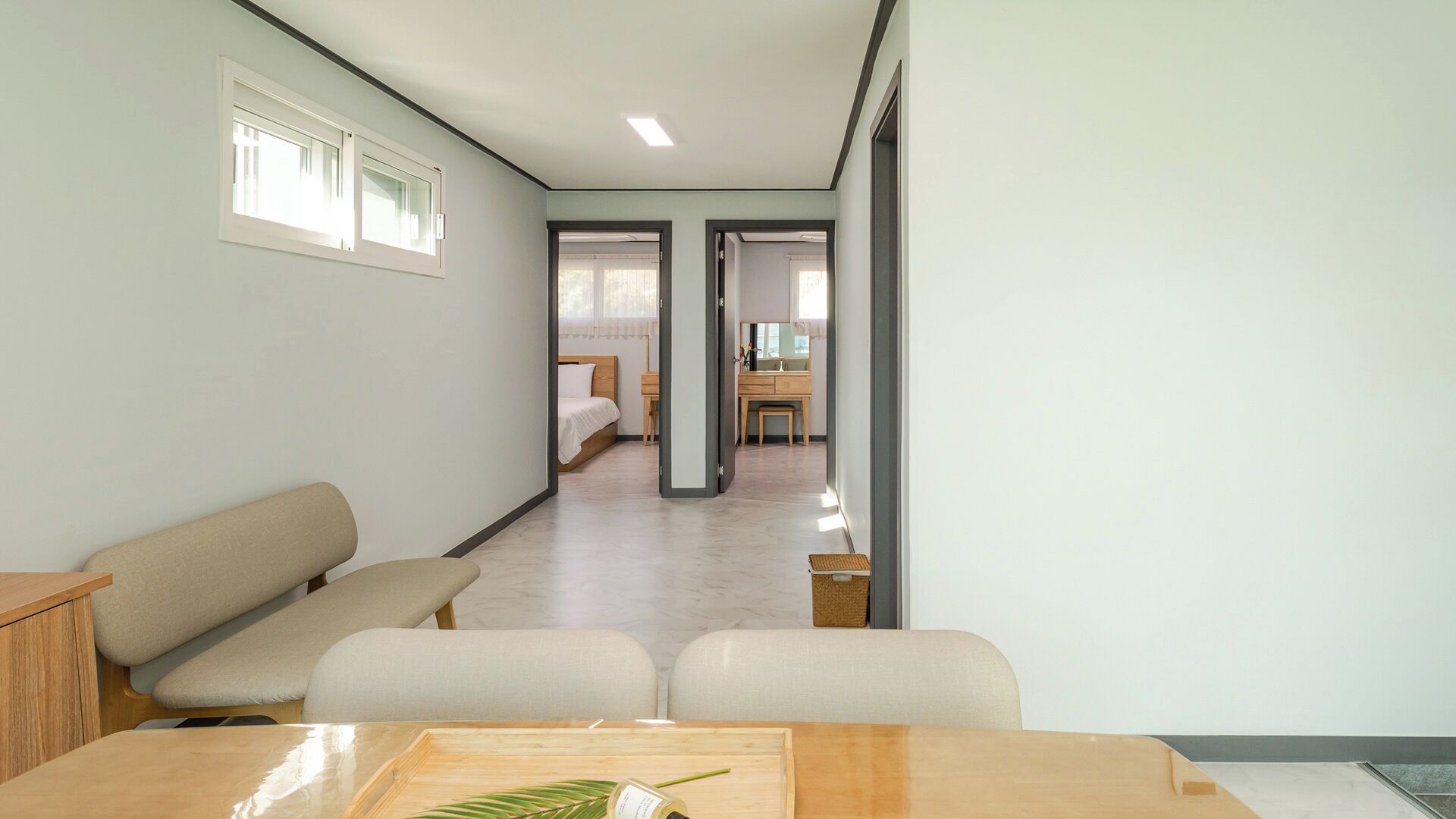 A hotel room with a bed, a desk, a chair, a small table, and a window.