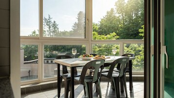 Un comedor con una mesa y sillas, un tazón de ensalada y dos copas de vino blanco.