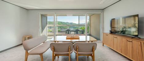 A modern living room with a flat-screen TV, a sofa, and a dining table.