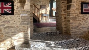Ein Zimmer mit Stehwänden, einem gemusterten Boden und einer Holztreppe, mit Blick in einen anderen Raum.
