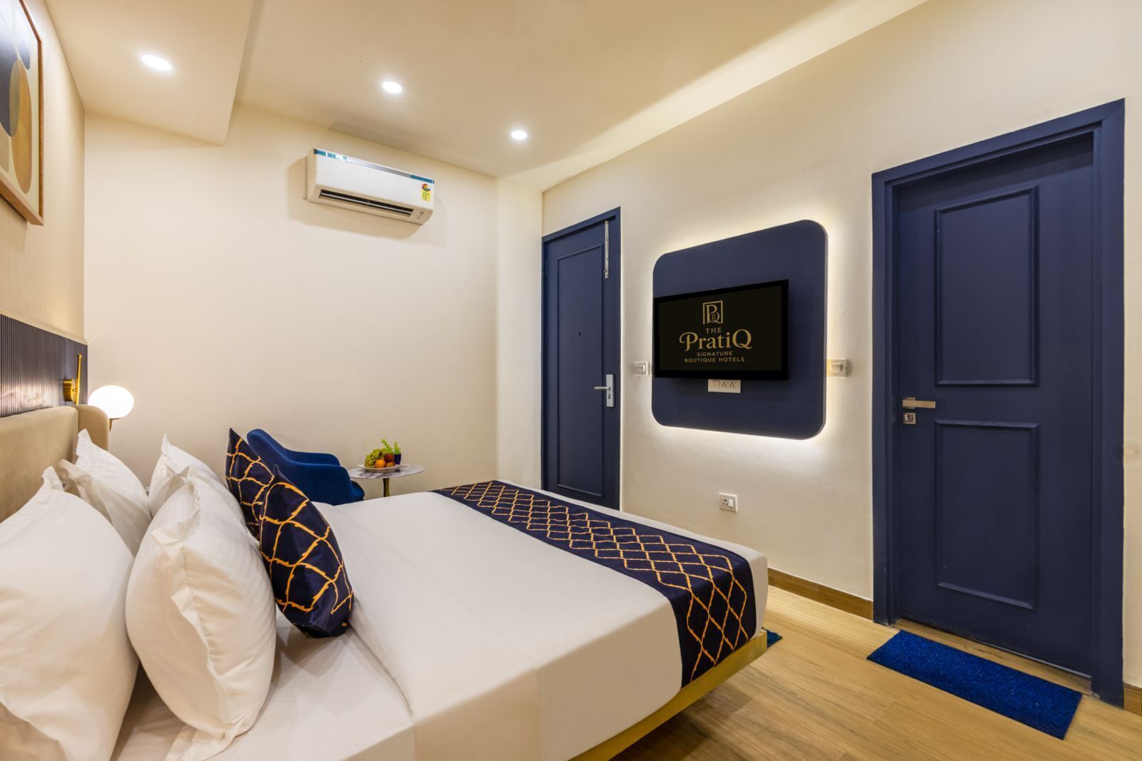 A hotel room with a bed, a TV mounted on the wall, and two doors.