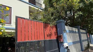 A gated residential area with a red and blue fence, a tree, and a sign for 'Café Luso'.