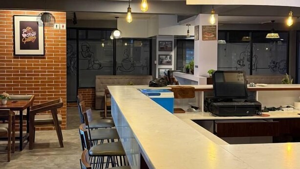 A modern bar area with a long counter, bar stools, and hanging light fixtures.