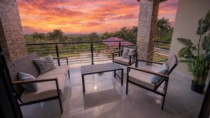 A balcony with a view of a sunset, a sofa, a table, and chairs. - Puerto Plata | Modern Villa Pool+BBQ+WiFi+Security (Puerto Plata)