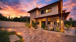 A modern two-story house with a stone-paved driveway, a covered porch, and a landscaped garden. - Puerto Plata | Modern Villa Pool+BBQ+WiFi+Security (Puerto Plata)