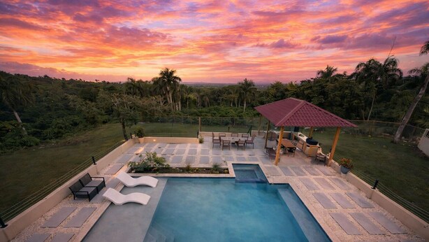 A swimming pool with a pergola and seating area, surrounded by lush greenery. - Puerto Plata | Modern Villa Pool+BBQ+WiFi+Security (Puerto Plata)