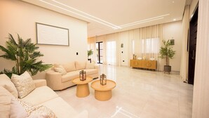 A modern living room with a sofa, two round coffee tables, and a large window with curtains. - Puerto Plata | Modern Villa Pool+BBQ+WiFi+Security (Puerto Plata)