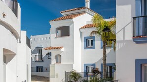 A narrow street with white buildings, blue windows, and a cobblestone path. - Exclusive Penthouse in Paraíso Pueblo – Style & Serenity (Benahavís)