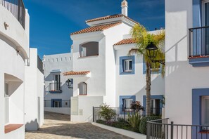 A narrow street with white buildings, blue windows, and a cobblestone path. - Exclusive Penthouse in Paraíso Pueblo – Style & Serenity (Benahavís)