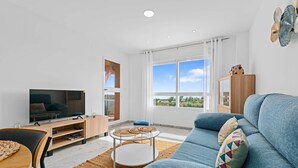 Un salon moderne avec un téléviseur, un canapé et un coin repas.