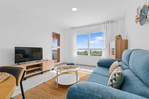 A modern living room with a TV, sofa, and dining area. - Los Hidalgos Seaview Pool and relax (Manilva)