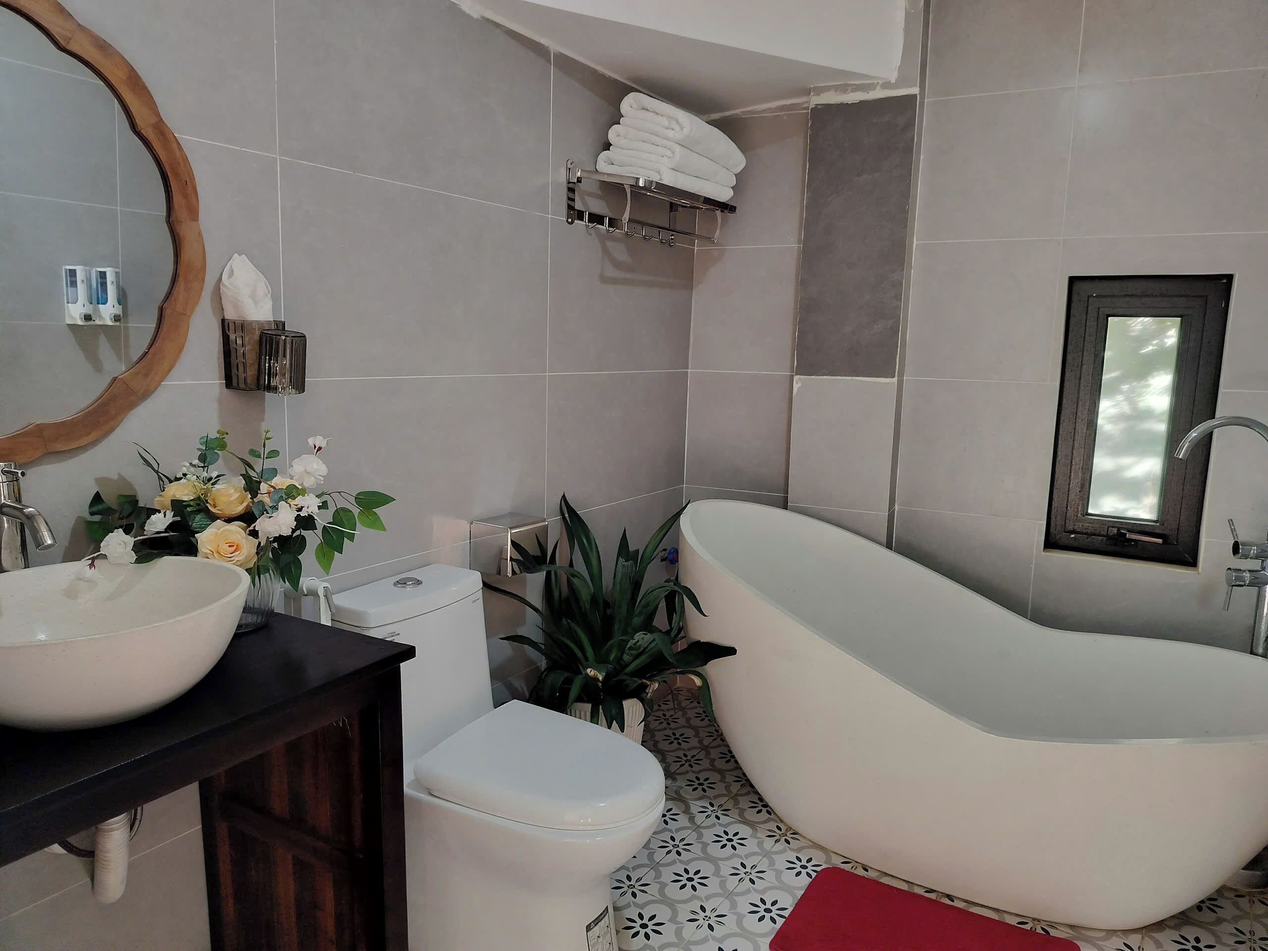 Een moderne badkamer met een vrijstaand bad, een grote spiegel, een wastafel en een toilet.