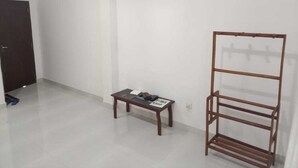 Una stanza con una rastrelliera in legno, un tavolino con un libro e un telefono, e una porta.