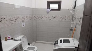 Un bagno piccolo con il water, una lavatrice e un piccolo oblò.