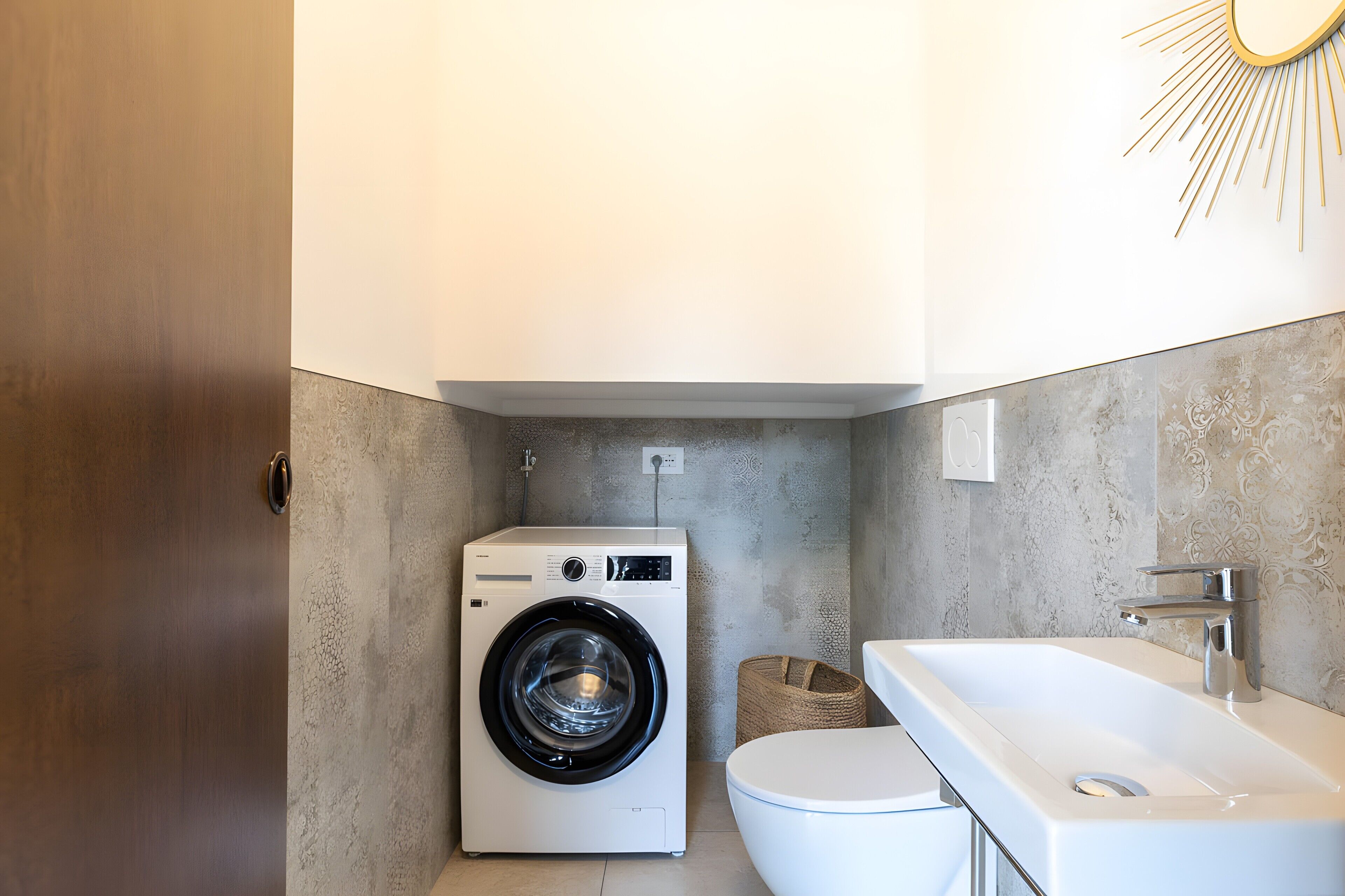 Een kleine badkamer met een wasmachine, toilet en een groot wastafel.