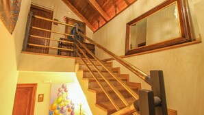 A wooden staircase with a handrail, a large mirror on the wall, and a painting of colorful spheres on the wall. - El Alboroque (Tramacastilla de Tena)