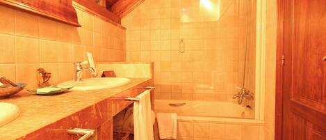 A bathroom with two sinks, a bathtub, and a shower.