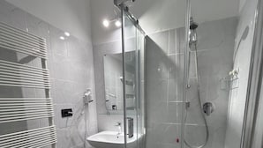 Une salle de bain moderne avec une douche à parois de verre, un lavabo et un miroir.