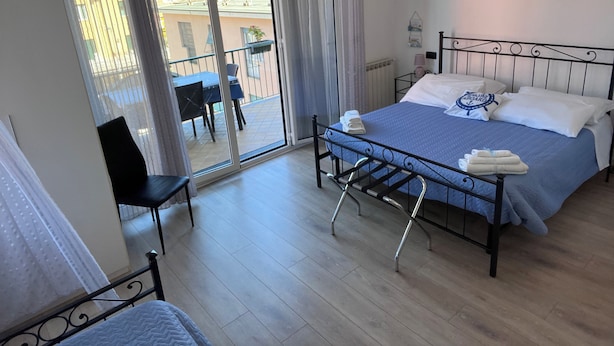 Une chambre à coucher comprenant un lit, une chaise, une table et un balcon avec vue sur les immeubles.