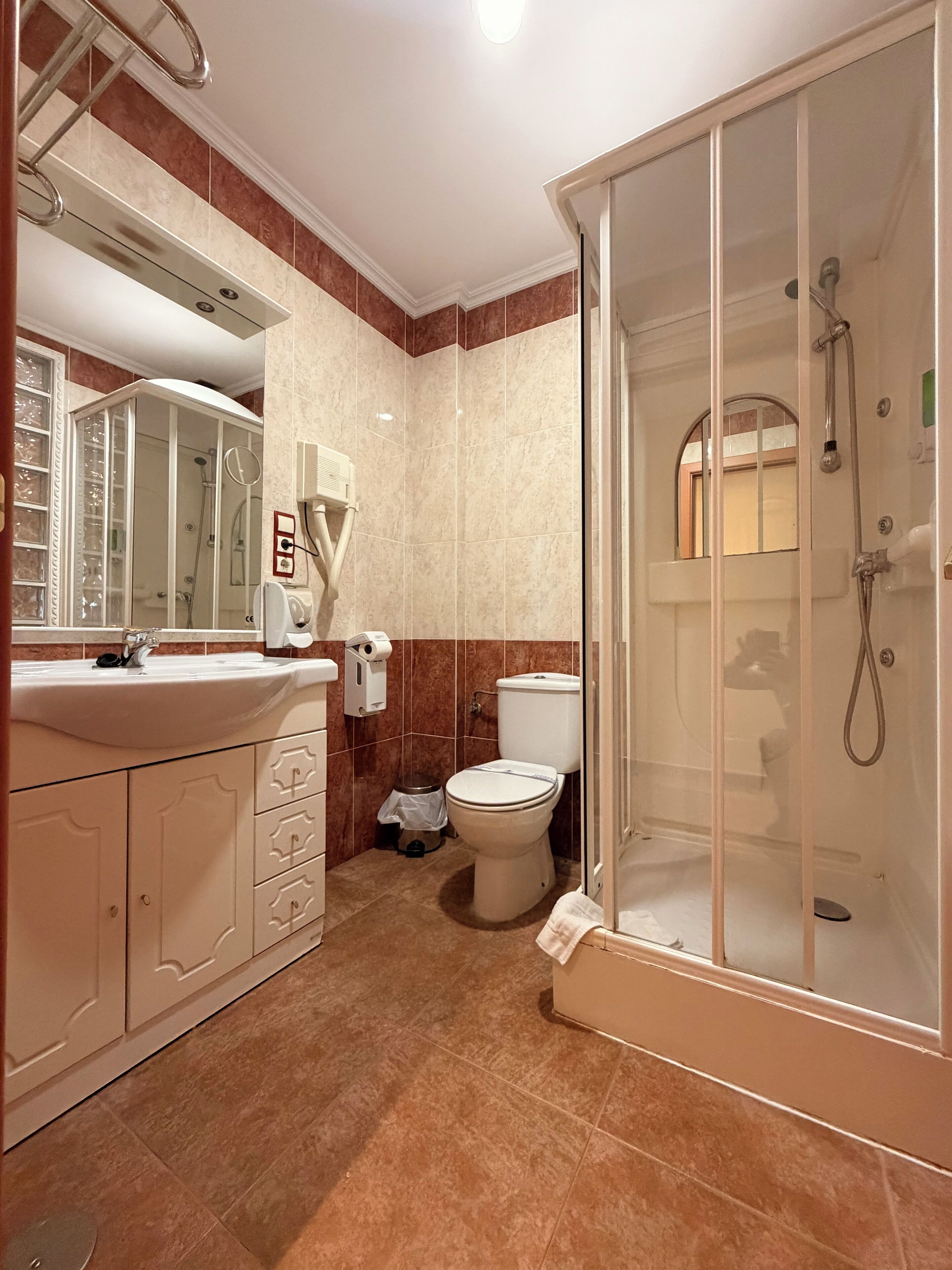 A bathroom with a glass-enclosed shower, a sink with a mirror, and a toilet.
