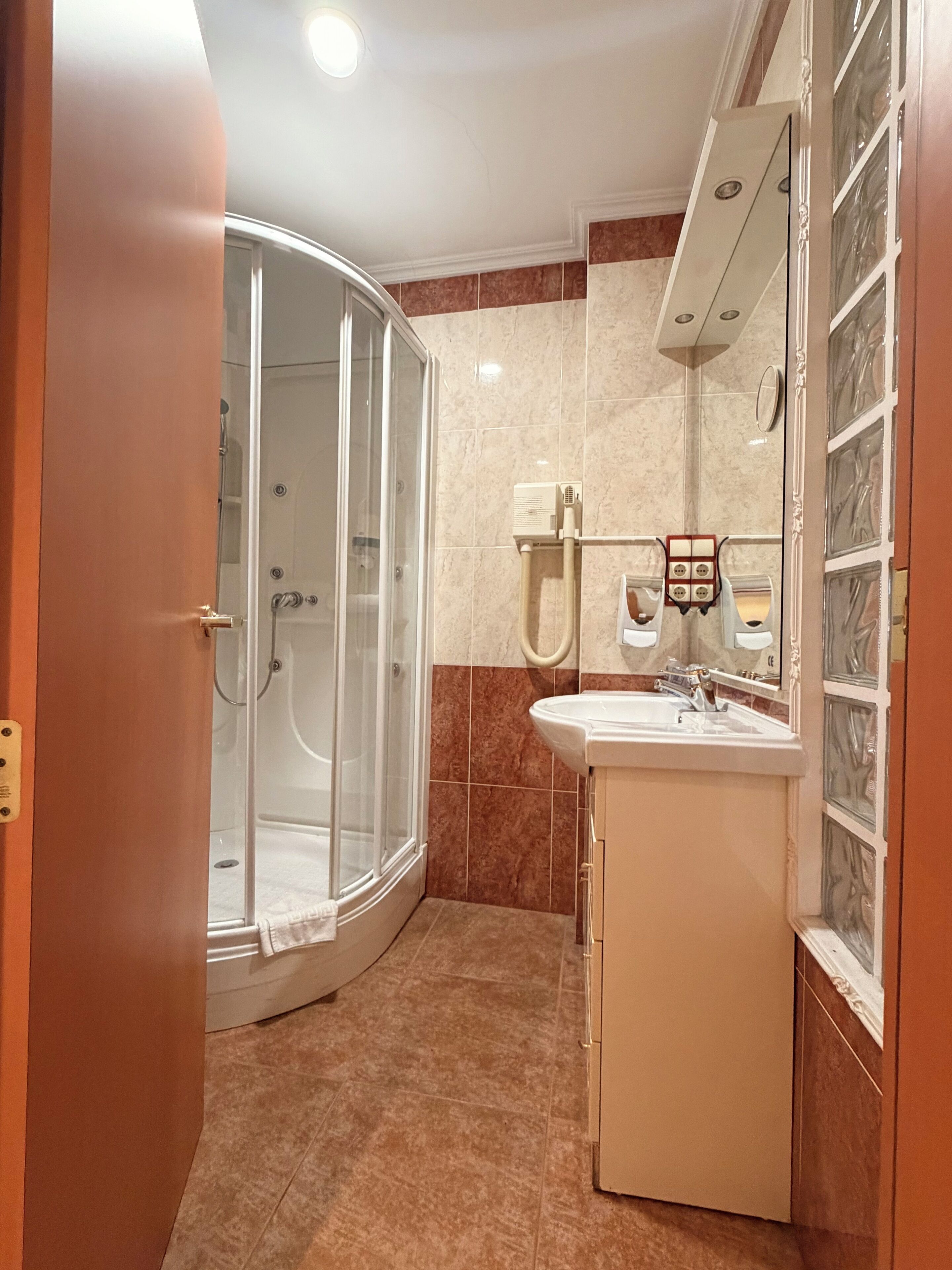 Un baño con cabina de ducha de vidrio, un lavabo y un espejo con marco decorativo.