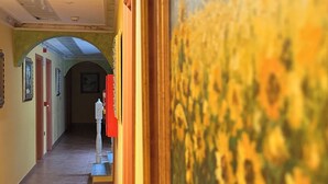 Un couloir doté d’un sol carrelé, de tableaux encadrés et d’un panneau rouge.