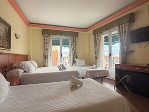 Een hotelkamer met twee bedden, een televisie, een bureau en een balkon met gordijnen.