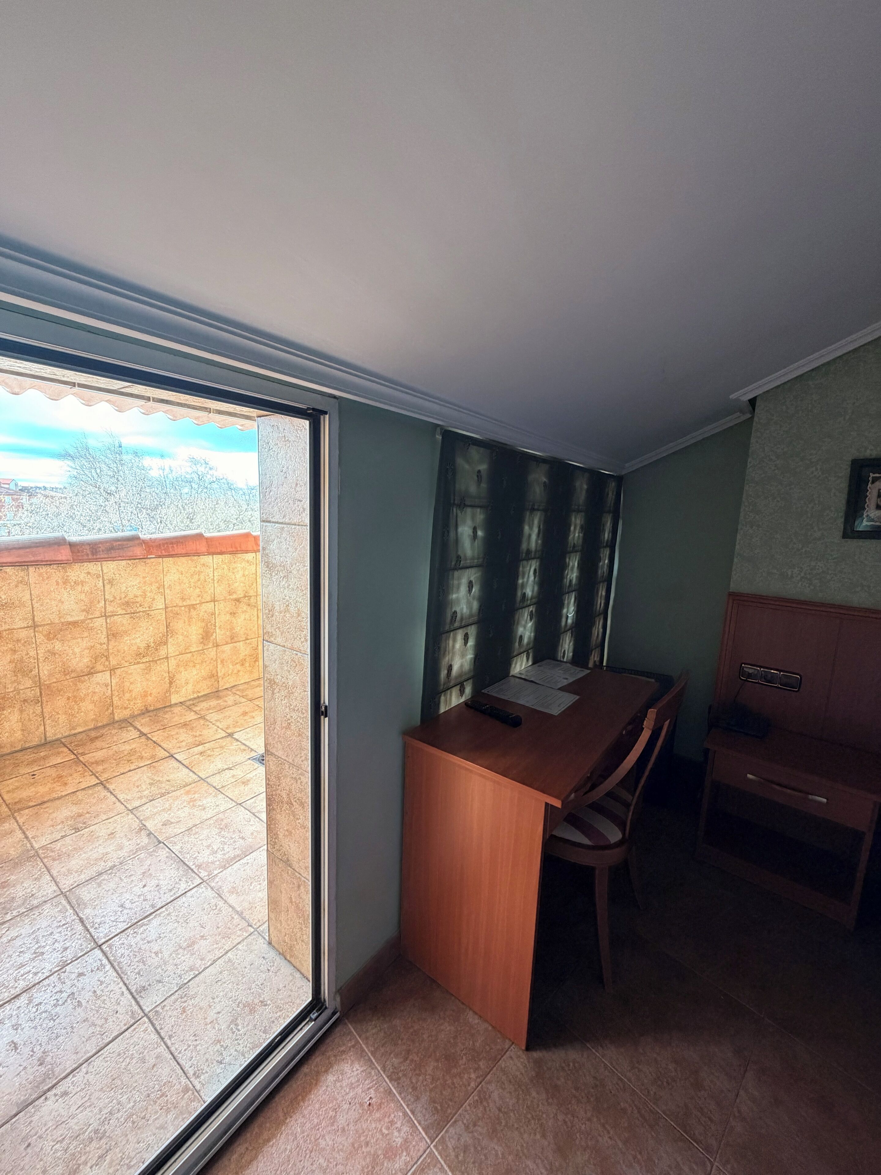A small office space with a desk, chair, and a view through a sliding glass door.