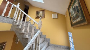 Un escalier avec des rampes en marbre menant à un palier, un tableau accroché au mur et une fenêtre avec du verre teinté en bleu.