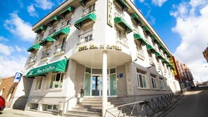 Un hôtel au style architectural classique, avec une entrée principale surélevée par des marches, de nombreux balcons et une enseigne indiquant qu’il s’agit d’un hôtel.