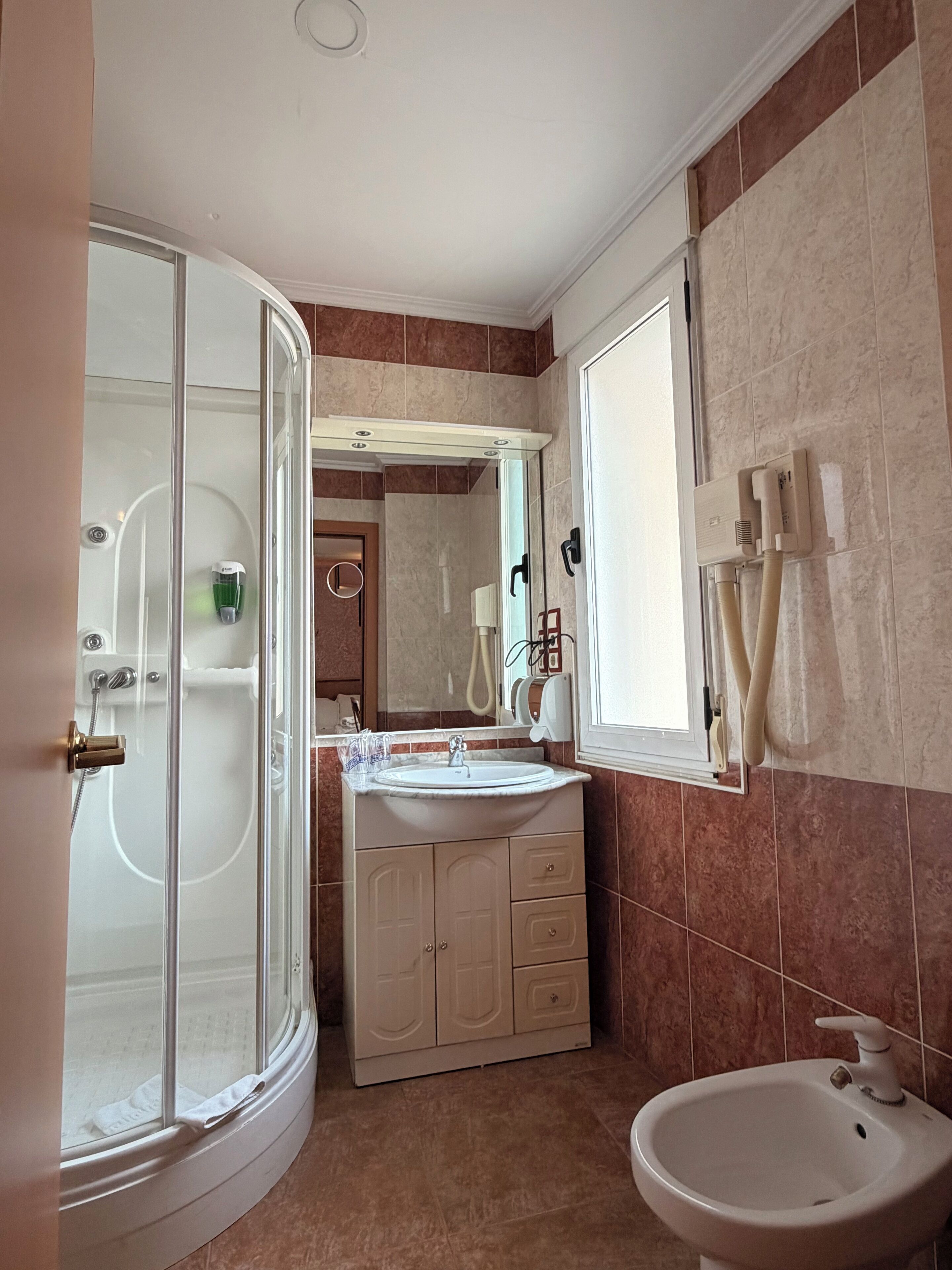 A bathroom with a glass shower enclosure, a sink with a mirror, and a toilet.