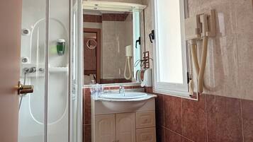 Un bagno con cabina doccia in vetro, lavandino con specchio e water.