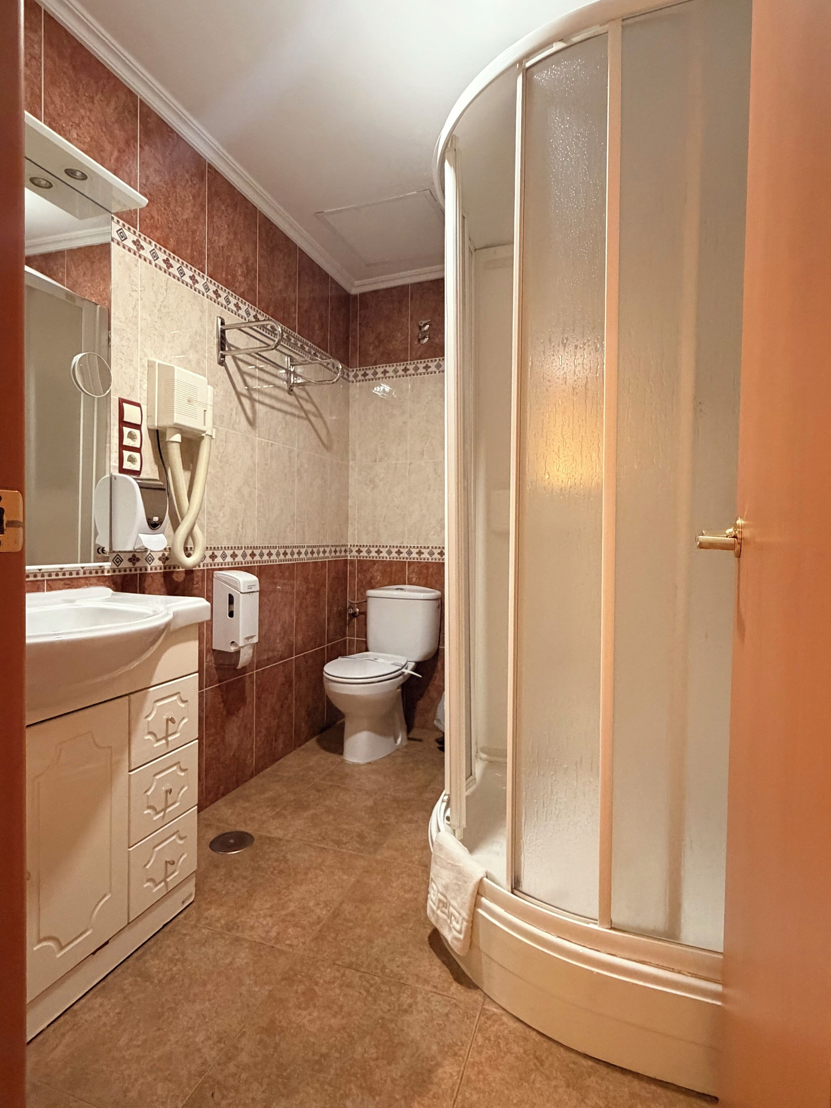 A bathroom with a sink, mirror, towel rack, toilet, and a shower enclosure.