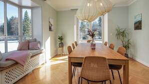 En matplats med ett långt träbord, flätade stolar och en bänk med kuddar.