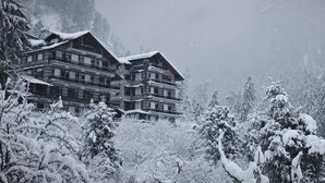 A multi-story lodge with balconies, surrounded by snow-covered trees and mountains. - Manali Se - Your Home in the Pines (Jagatsukh)