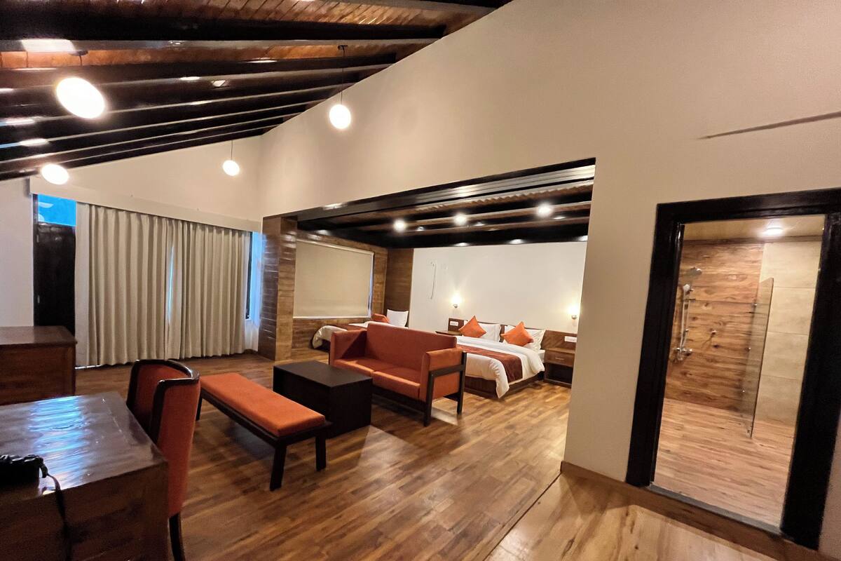 A spacious room with a wooden floor, a sofa, a bed, and a dining area.
