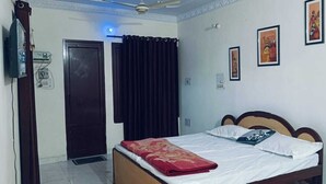A bedroom with a bed, a ceiling fan, a door, and a wall-mounted TV. - The PFNL Residency (Gohana)