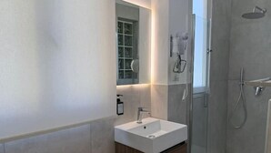 A modern bathroom with a glass-enclosed shower, a white sink, and a mirror with a built-in light. - Riviera Collection - Dream Lofts in the Heart of Naples (Napoli)