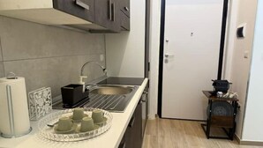 A compact kitchen with a sink, a small countertop, and a door leading to another room. - Riviera Collection - Dream Lofts in the Heart of Naples (Napoli)