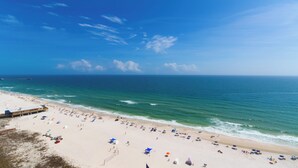 Ein Strand mit einem Steg, Sonnenschirmen und Menschen.