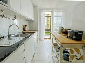 Una cocina moderna con armarios blancos, un lavamanos de acero inoxidable y una tostadora sobre la encimera.