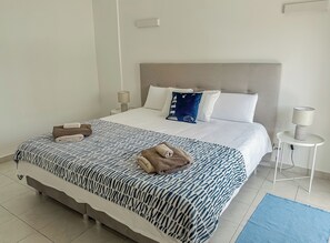 A neatly made bed with a patterned bedspread, two pillows, and a bedside lamp on a small table. - BnB Homes vibrant Ocean View terraced apartment with swimming pool 200m to beach (Armação de Pêra)