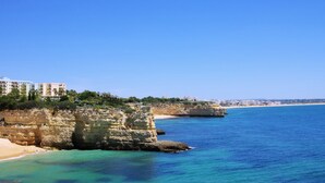 Ein Hotel an der Küste mit Blick auf einen Strand, felsige Klippen und ein klares blaues Meer.